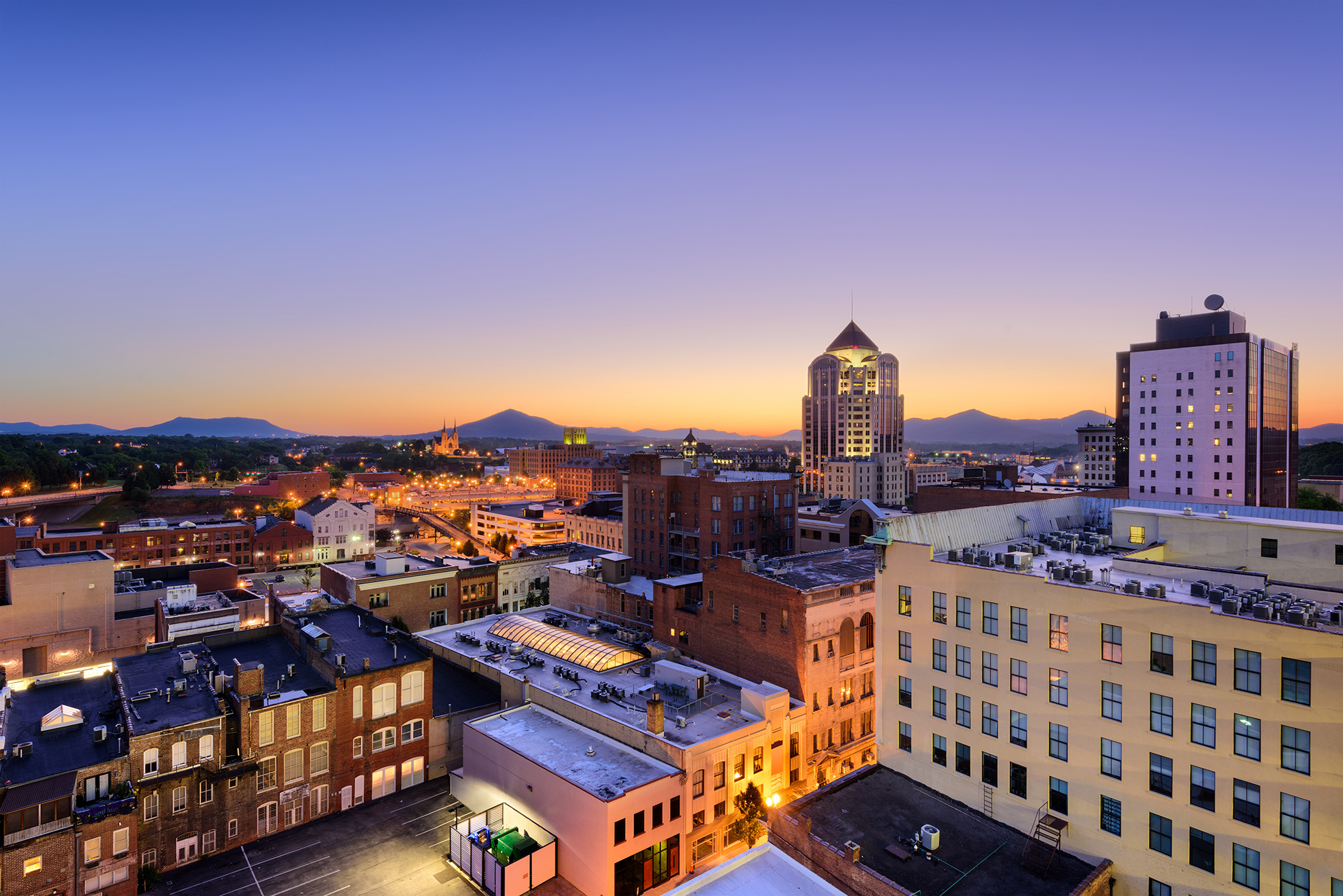 Downtown Roanoke, Virginia skyline at dusk with the Blue Ridge Mountains beyond